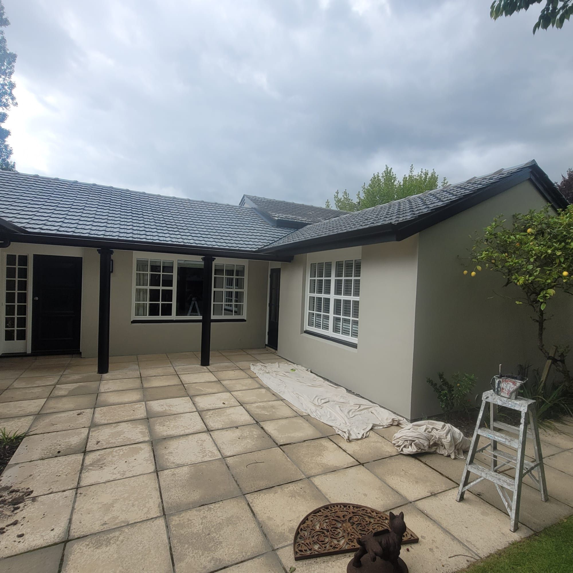 Single-storey home repainted grey with a paved drive